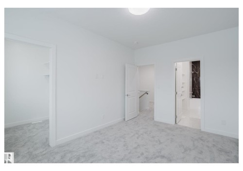 Unfurnished bedroom with a walk in closet, light colored carpet, and ensuite bathroom - 231 25 Street Sw, Edmonton, AB - Indoor Photo Showing Other Room