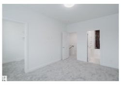Unfurnished bedroom with a walk in closet, light colored carpet, and ensuite bathroom - 