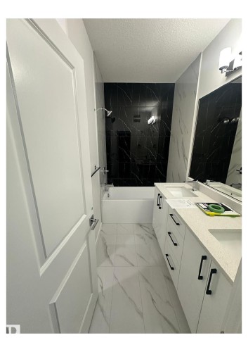 Full bathroom with light marble finish flooring, double vanity, a combined bath / shower with marble appearance, and a textured ceiling - 231 25 Street Sw, Edmonton, AB - Indoor
