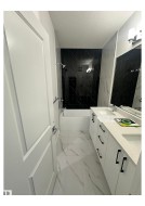 Full bathroom with light marble finish flooring, double vanity, a combined bath / shower with marble appearance, and a textured ceiling - 