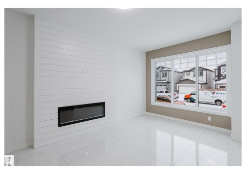 Unfurnished living room featuring a large fireplace and light marble finish flooring - 231 25 Street Sw, Edmonton, AB - Indoor With Fireplace