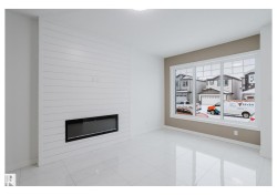 Unfurnished living room featuring a large fireplace and light marble finish flooring - 