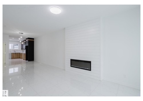 Unfurnished living room with a fireplace and light marble finish flooring - 231 25 Street Sw, Edmonton, AB - Indoor