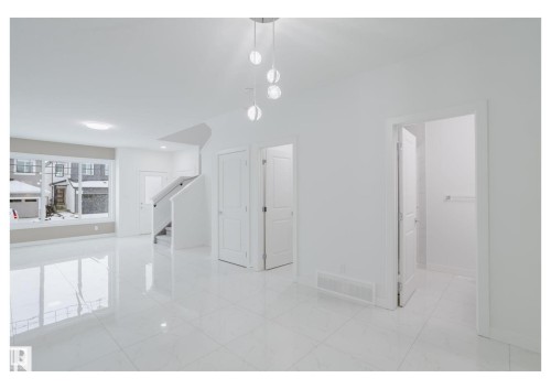 Unfurnished dining area featuring stairway and light marble finish floors - 231 25 Street Sw, Edmonton, AB - Indoor Photo Showing Other Room