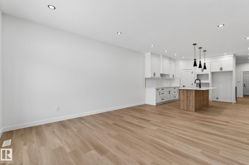 Two tone kitchen with a center island with sink, open floor plan, light wood finished floors, pendant lighting, and two tone cabinetry - 3318 Chickadee Drive, Edmonton, AB - Indoor Photo Showing Kitchen