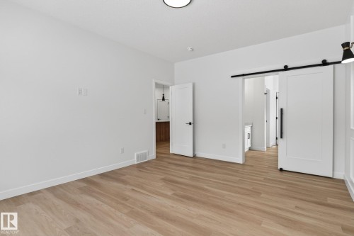 Unfurnished bedroom featuring a barn door and light wood finished floors - 3318 Chickadee Drive, Edmonton, AB - Indoor Photo Showing Other Room