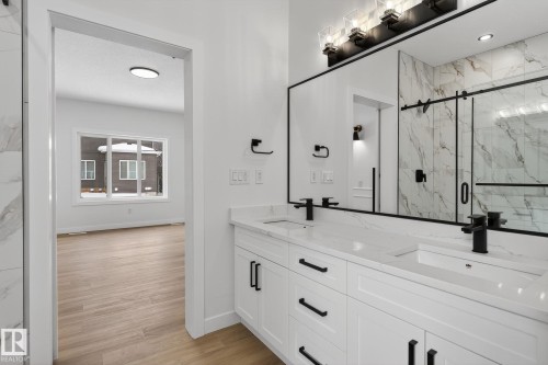 Bathroom with double vanity, a marble finish shower, and light wood-style floors - 3318 Chickadee Drive, Edmonton, AB - Indoor Photo Showing Other Room