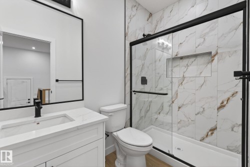 Full bathroom featuring vanity, a marble finish shower, and wood finished floors - 3318 Chickadee Drive, Edmonton, AB - Indoor Photo Showing Bathroom