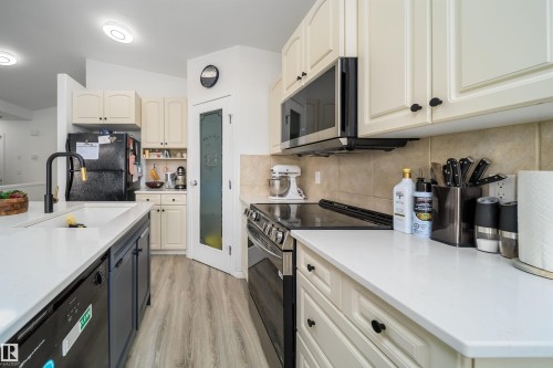 Kitchen with electric stove, two tone color scheme, decorative backsplash, stainless steel microwave, and dishwasher - 1179 Oakland Drive, Devon, AB - Indoor Photo Showing Kitchen With Upgraded Kitchen