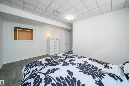 Bedroom with dark wood-style floors, a closet, a paneled ceiling, and wooden walls - 1179 Oakland Drive, Devon, AB - Indoor Photo Showing Bedroom
