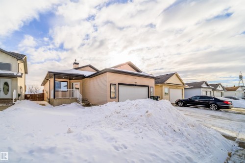 View of front of home featuring an attached garage and a chimney - 1179 Oakland Drive, Devon, AB - Outdoor With Facade