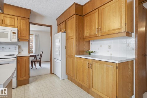 Kitchen featuring white appliances, light countertops, backsplash, a textured ceiling, and wood finish cabinets - 65 Lorne Crescent, St. Albert, AB - Indoor Photo Showing Kitchen