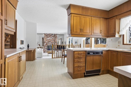Kitchen featuring wood finish cabinets, light countertops, a peninsula, brick patterned floors, and a fireplace - 65 Lorne Crescent, St. Albert, AB - Indoor Photo Showing Kitchen