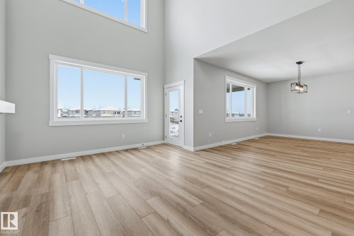 Unfurnished living room featuring light wood-style flooring, healthy amount of natural light, and a high ceiling - 28 Harley Way, Spruce Grove, AB - Indoor Photo Showing Other Room