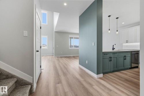Bar with dual tone cabinetry, light wood-type flooring, decorative light fixtures, and dishwasher - 28 Harley Way, Spruce Grove, AB - Indoor
