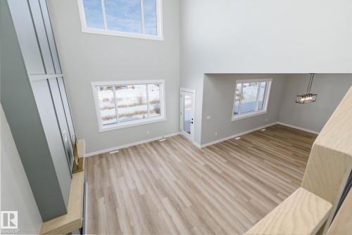 Unfurnished living room with light wood-type flooring and a high ceiling - 28 Harley Way, Spruce Grove, AB - Indoor Photo Showing Other Room
