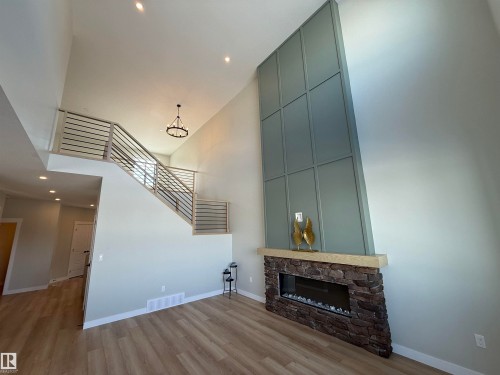 Unfurnished living room with recessed lighting, a high ceiling, a stone fireplace, and light wood finished floors - 28 Harley Way, Spruce Grove, AB - Indoor With Fireplace