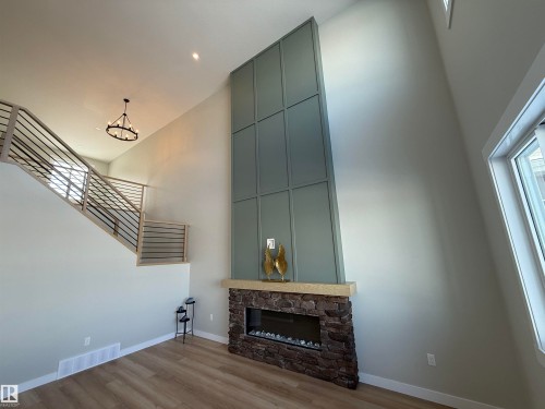Unfurnished living room with a high ceiling, a fireplace, and wood finished floors - 28 Harley Way, Spruce Grove, AB - Indoor With Fireplace