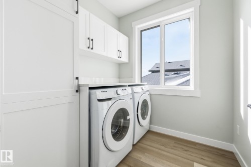 Laundry area featuring cabinet space, light wood-style floors, and washer and clothes dryer - 28 Harley Way, Spruce Grove, AB - Indoor Photo Showing Laundry Room