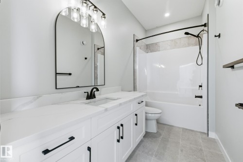 Bathroom featuring vanity, washtub / shower combination, and light tile patterned floors - 28 Harley Way, Spruce Grove, AB - Indoor Photo Showing Bathroom