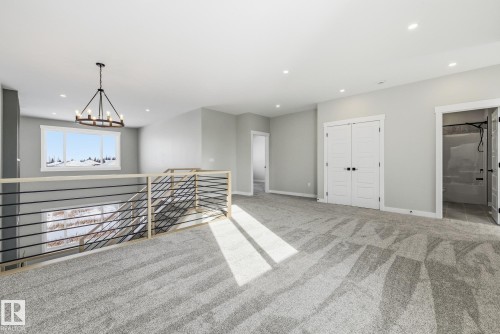 Carpeted spare room featuring baseboards and suspended lighting - 28 Harley Way, Spruce Grove, AB - Indoor