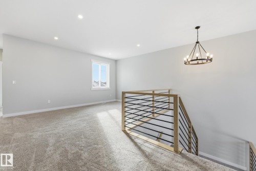 Unfurnished room featuring light carpet and suspended lighting - 28 Harley Way, Spruce Grove, AB - Indoor