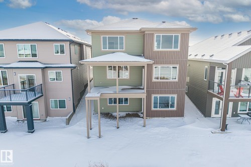 Snow covered back of property featuring a patio, a residential view, and a deck - 28 Harley Way, Spruce Grove, AB - Outdoor