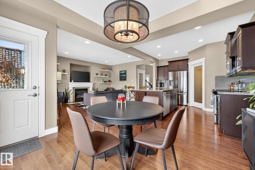 Dining space featuring a glass covered fireplace, suspended lighting, and light wood-style flooring - 21 Dittrich, Fort Saskatchewan, AB - Indoor Photo Showing Dining Room