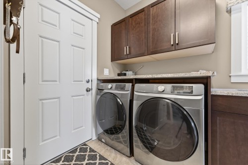 Laundry room with cabinet space, washing machine and clothes dryer, and light tile patterned floors - 21 Dittrich, Fort Saskatchewan, AB - Indoor Photo Showing Laundry Room