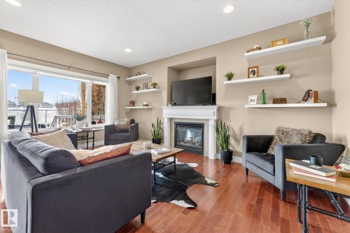 Living area with wood finished floors, a tiled fireplace, recessed lighting, and a textured ceiling - 21 Dittrich, Fort Saskatchewan, AB - Indoor Photo Showing Living Room With Fireplace