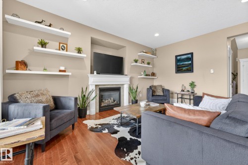 Living room with wood finished floors, a glass covered fireplace, and recessed lighting - 21 Dittrich, Fort Saskatchewan, AB - Indoor Photo Showing Living Room With Fireplace
