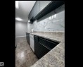 Kitchen with light countertops, white dishwasher, backsplash, a textured ceiling, and dark stone finish floors - 302 49 Akins Drive, St. Albert, AB  - Indoor Photo Showing Other Room 