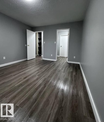 Unfurnished bedroom with a textured ceiling and dark wood-type flooring - 302 49 Akins Drive, St. Albert, AB - Indoor Photo Showing Other Room
