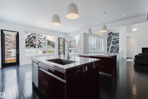 Kitchen with hanging light fixtures, open floor plan, dark wood-type flooring, modern cabinets, and light stone counters - 6307 125 Street, Edmonton, AB - Indoor Photo Showing Kitchen