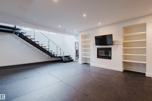 Unfurnished living room featuring built in features, a glass covered fireplace, and recessed lighting - 6307 125 Street, Edmonton, AB - Indoor With Fireplace