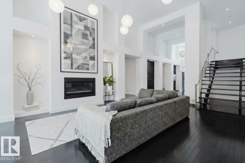 Living area featuring a high ceiling, a glass covered fireplace, and dark wood-style flooring - 6307 125 Street, Edmonton, AB - Indoor With Fireplace
