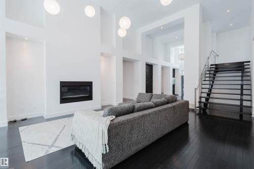 Living area with a high ceiling, a glass covered fireplace, dark wood-type flooring, and recessed lighting - 6307 125 Street, Edmonton, AB - Indoor With Fireplace