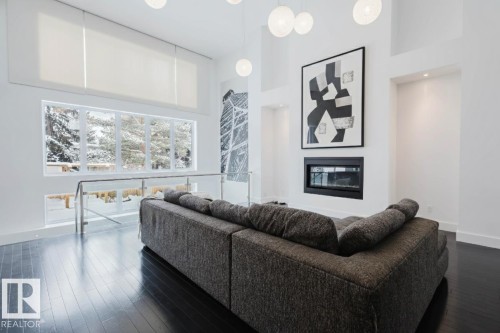 Living area with a glass covered fireplace, a high ceiling, and dark wood-style flooring - 6307 125 Street, Edmonton, AB - Indoor Photo Showing Living Room With Fireplace