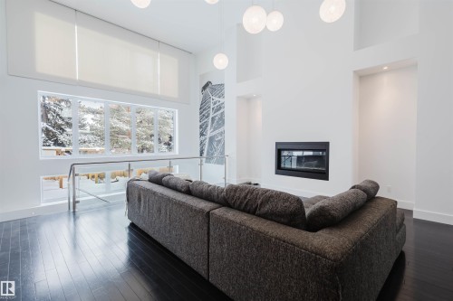 Living area featuring a high ceiling, a glass covered fireplace, and dark wood finished floors - 6307 125 Street, Edmonton, AB - Indoor Photo Showing Living Room With Fireplace