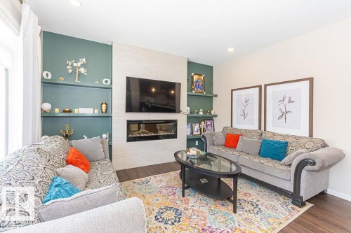 Living area featuring built in features, a fireplace, and wood finished floors - 3128 13 Avenue, Edmonton, AB - Indoor Photo Showing Living Room With Fireplace