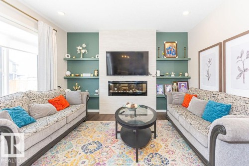 Living area featuring wood finished floors, built in shelves, and a tile fireplace - 3128 13 Avenue, Edmonton, AB - Indoor Photo Showing Living Room With Fireplace