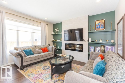 Living area featuring wood finished floors, built in features, and a tiled fireplace - 3128 13 Avenue, Edmonton, AB - Indoor Photo Showing Living Room With Fireplace