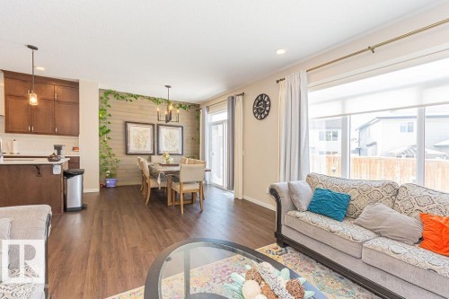 Living room with dark wood-style floors, suspended lighting, and an accent wall - 3128 13 Avenue, Edmonton, AB - Indoor Photo Showing Living Room