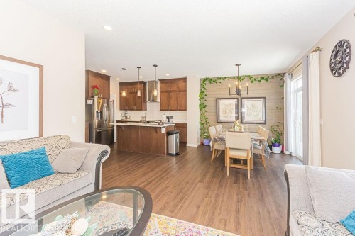 Living room with dark wood-type flooring, suspended lighting, and an accent wall - 3128 13 Avenue, Edmonton, AB - Indoor