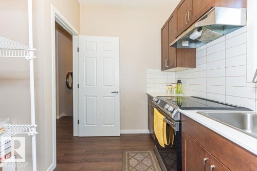 Kitchen with wood finish cabinets, electric range, light countertops, dark wood-style flooring, and backsplash - 3128 13 Avenue, Edmonton, AB - Indoor Photo Showing Kitchen