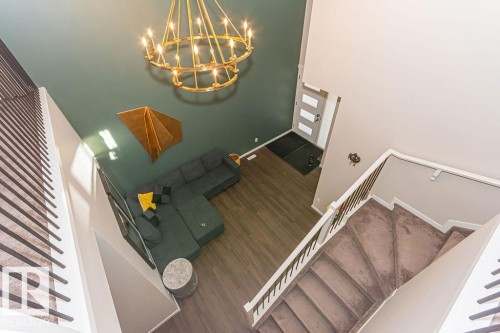 Stairs with a high ceiling, a chandelier, and wood finished floors - 3128 13 Avenue, Edmonton, AB - Indoor Photo Showing Other Room