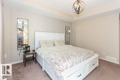 Bedroom with a raised ceiling, light colored carpet, a chandelier, and wallpapered walls - 3128 13 Avenue, Edmonton, AB - Indoor Photo Showing Bedroom