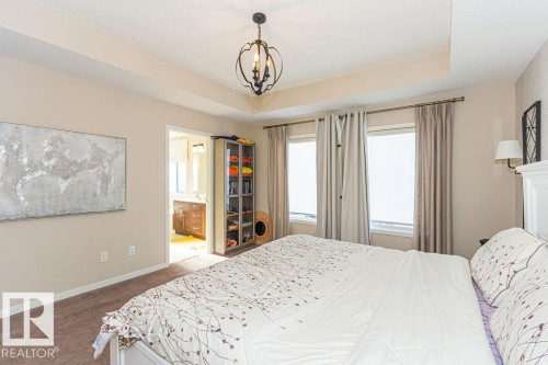 Bedroom with carpet, ensuite bathroom, suspended lighting, and a raised ceiling - 3128 13 Avenue, Edmonton, AB - Indoor Photo Showing Bedroom