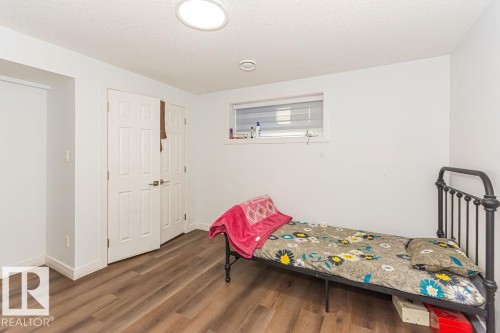 Bedroom with dark wood-type flooring, a textured ceiling, and a closet - 3128 13 Avenue, Edmonton, AB - Indoor
