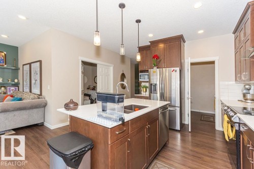 Kitchen with pendant lighting, open floor plan, stainless steel appliances, wood finish cabinets, and an island with sink - 3128 13 Avenue, Edmonton, AB - Indoor Photo Showing Kitchen With Upgraded Kitchen